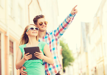 Image showing smiling couple with tablet pc in city