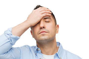 Image showing unhappy man with closed eyes touching his forehead