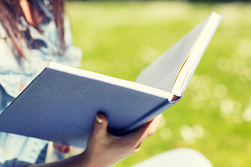 Image showing close up of young girl with book in park
