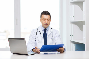 Image showing male doctor with clipboard and laptop in office