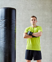 Image showing man with boxing gloves and punching bag in gym