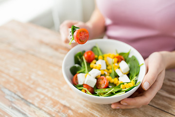 Image showing close up of young woman eating salad at home