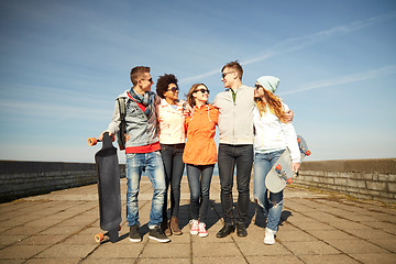 Image showing happy teenage friends with longboards on street