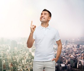 Image showing smiling man pointing finger up over city