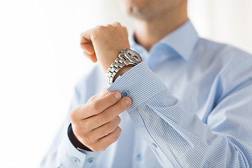 Image showing close up of man fastening buttons on shirt sleeve