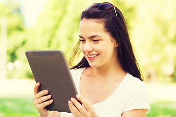 Image showing smiling young girl with tablet pc sitting on grass