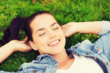 Image showing smiling young girl with closed eyes lying on grass