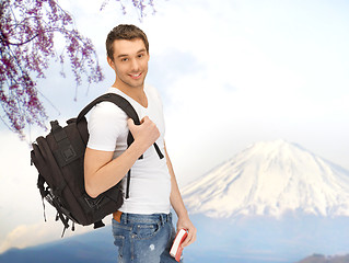 Image showing happy young man with backpack and book travelling