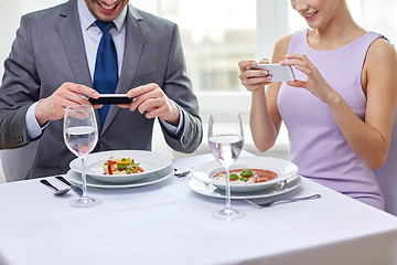 Image showing close up of couple with smartphones at restaurant