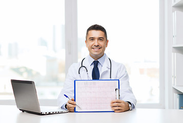 Image showing happy doctor with clipboard and laptop in office