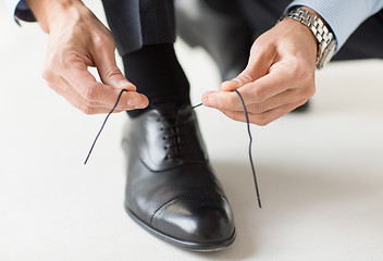 Image showing close up of man leg and hands tying shoe laces