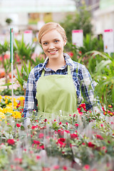 Image showing happy woman with flowers in greenhouse