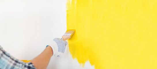 Image showing close up of male in gloves painting a wall