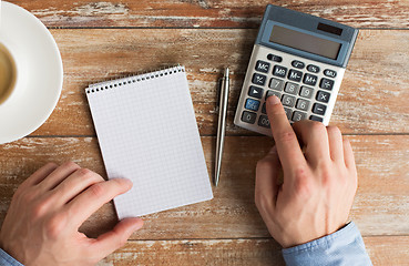 Image showing close up of hands with calculator and notebook