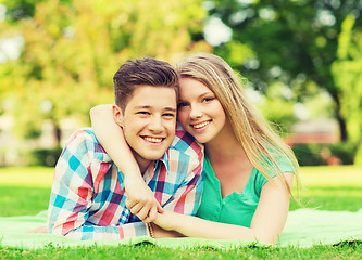 Image showing smiling couple lying on blanket in park