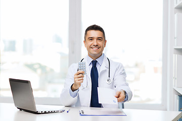 Image showing smiling doctor with tablets and laptop in office