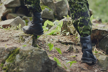 Image showing close up of soldier climbing on rocks in forest