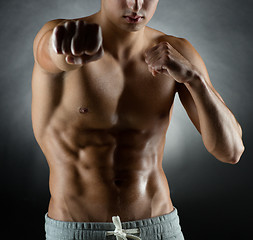 Image showing young man on fighting stand over black background