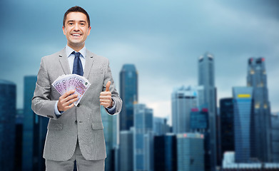 Image showing smiling businessman with money showing thumbs up
