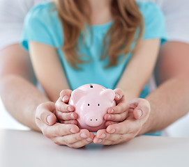 Image showing close up of family hands with piggy bank