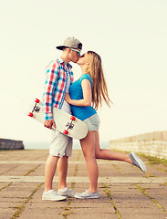 Image showing smiling couple with skateboard kissing outdoors