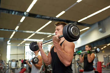 Image showing young men flexing muscles with barbells in gym