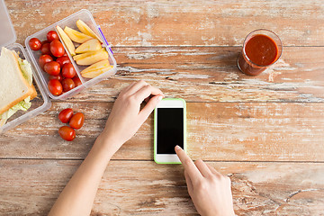 Image showing close up of hands with smartphone food on table