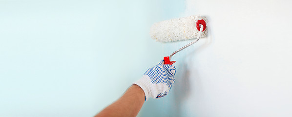 Image showing close up of male in gloves painting wall