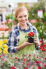 Image showing happy woman holding flowers in greenhouse