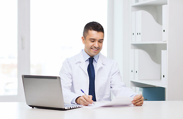 Image showing smiling male doctor with laptop in medical office