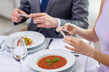 Image showing close up of couple with smartphones at restaurant