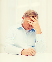 Image showing stressed old man holding head at home