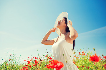 Image showing smiling young woman in straw hat on poppy field