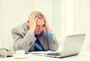 Image showing upset older businessman with laptop and telephone