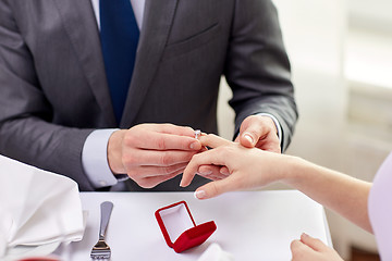 Image showing close up of man putting ring to his fiance finger