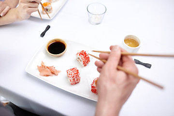 Image showing close up of couple eating sushi at restaurant