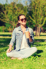 Image showing smiling young girl with cup of coffee in park