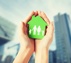 Image showing hands holding green house with family