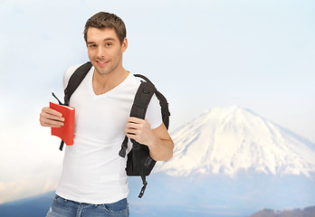 Image showing happy young man with backpack and book travelling