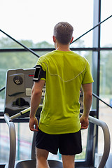 Image showing man exercising on treadmill in gym from back