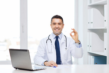 Image showing smiling doctor with laptop showing ok in office