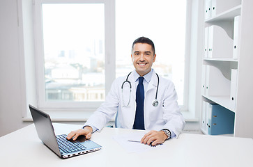 Image showing smiling male doctor with laptop in medical office