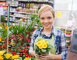 Image showing happy woman holding flowers in greenhouse