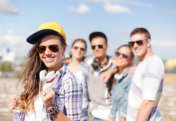 Image showing teenage girl with headphones and friends outside