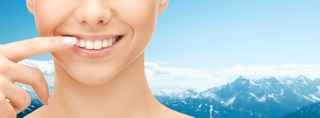 Image showing close up of smiling woman face pointing to teeth