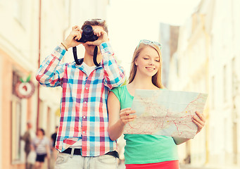 Image showing smiling couple with map and photo camera in city