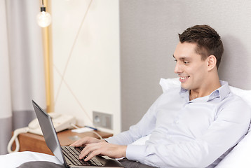 Image showing happy businesswoman with laptop in hotel room