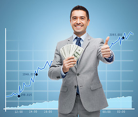 Image showing smiling businessman with money showing thumbs up