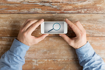 Image showing close up of hands with magnifier on smartphone