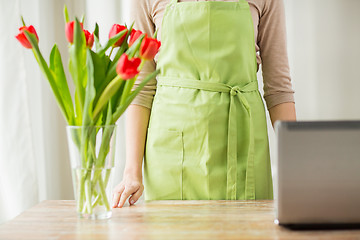 Image showing close up of woman with tulips in vase and laptop